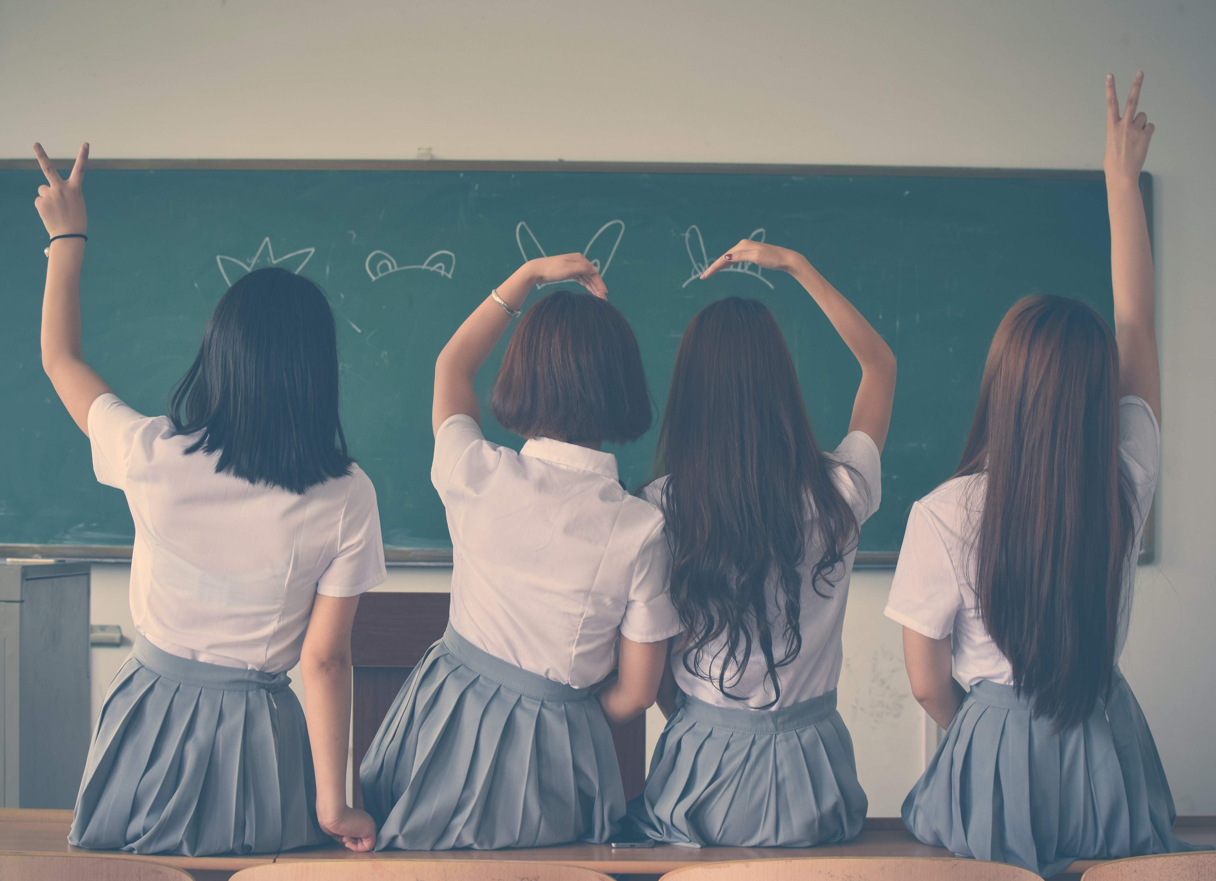 four girls in school uniforms face away from the camera